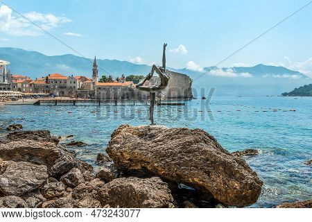 Budva, Montenegro - June 17, 2021: Budva Ballerina Statue In The Adriatic Sea Against The Backdrop O