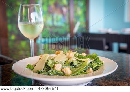 Caesar Salad Served With White Wine On A Table
