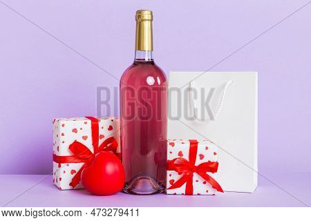 Bottle Of Wine On Colored Background For Valentine Day With Gift Box. Heart Shaped With Presrnt Box 