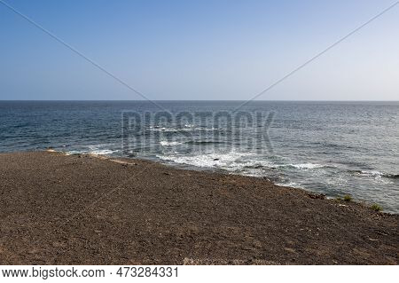 Southernmost Place Of The Island. Dry Dark Brown Volcanic Soil And A Calm Atlantic Ocean. Bright Blu