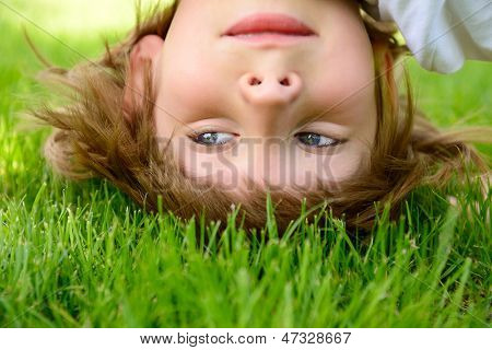 Glücklich kleiner Junge stehen kopfüber auf grünem Gras im Frühlingspark