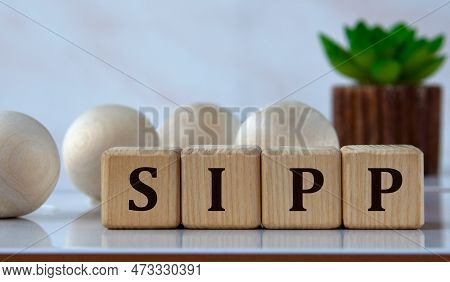 Sipp (self Invested Personal) - Acronym On Wooden Cubes Against The Background Of Light Balls And Ca