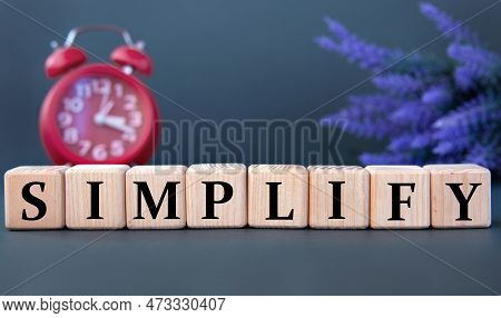 Simplify - Word On Wooden Cubes On A Gray Background With An Alarm Clock And A Branch Of Lavender
