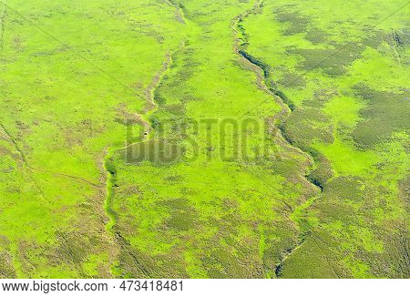 Vibrant Green Plain With Old Lava Stream Marks Seen From A Helicopter.