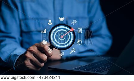 Businessman Using Magnifying Glass Focusing On Target Goal And Business Icons. Corporate Development