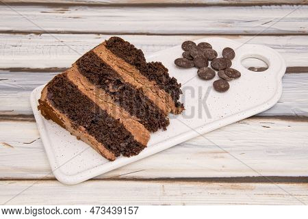 Portion Of Chocolate Cake With Three Layers Of Biscuits And Filling With Chocolate Chips On One Side