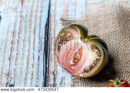 Image Of A Ripe Sweet Marmande Tomato Halved Looking Delicious On A Burlap On Top Of A Blue Table
