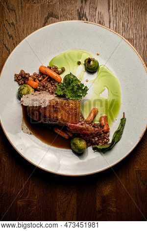 Top View On Plate With Piece Of Baked Pork Meat With Buckwheat And Vegetables And Sauce
