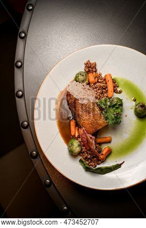 Top View On Plate With Fat Piece Of Baked Pork Meat With Buckwheat And Vegetables On Table