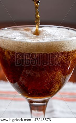 Pouring Of Belgian Abbey Brown Beer In Glass Close Up, White Foam And Bubbles In Glass