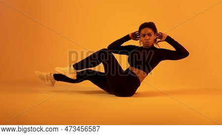 Fitness Workout. Black Sportswoman In Fitwear Doing Elbow To Knee Abs Crunch Exercising On Neon Oran