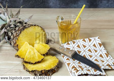 Pineapple Cut In Half And Pineapple Chunks On Top, Pineapple Juice In A Glass And Knife On A Cloth