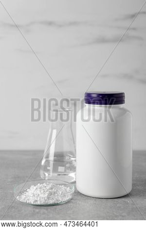 Petri Dish With Calcium Carbonate Powder, Jar And Laboratory Flask On Light Grey Table