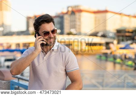 Portrait Of Handsome Man Chatting On Phone Outdoor. Stylish Man Talking On Phone Dressed In Polo. Fa