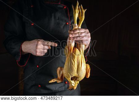 Presentation Of A Cock Before Cooking Fried Chicken. The Cook Points His Finger At The Chicken. Blac
