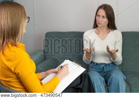 Woman Psychologist Talks And Helps Girl. Recording Important Studies In Tablet, View From Back Or Be