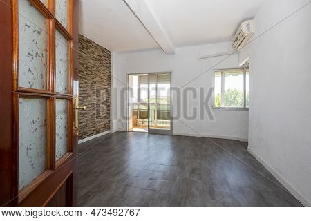 Empty Living Room With Gray Sintasol Floors, Sapele Wooden Door With Glass And Glazed Terrace In The