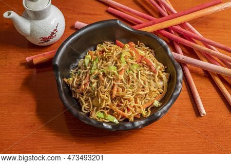 Black Bowl With Vegetable Noodles With Sauteed Carrot, Chopped Chives, Spring Onion And Onion And So