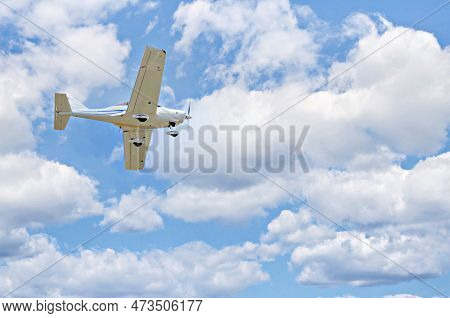 Single Engine Ultralight Plane Flying In The Blue Sky With White Clouds