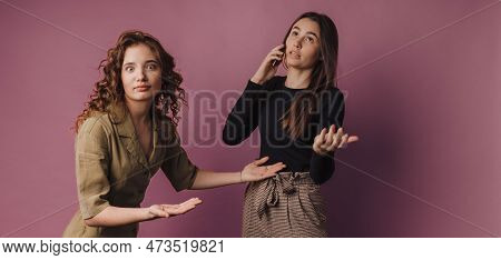 Studio Shoot Of Two Young Women, One Calling With Mobile Phone.