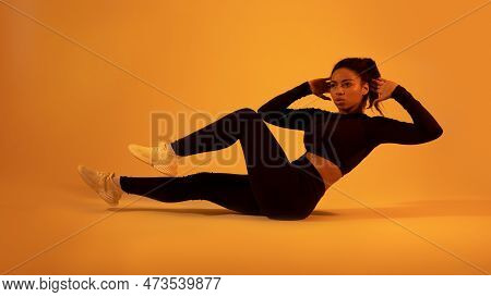Fitness Concept. Fit Black Woman Doing Elbow-to-knee Abdominal Crunch, Exercising On Floor On Neon O