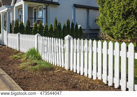 Nice New Wooden Fence Around House. Wooden White Picket Fence With Green Lawn. Street Photo, Nobody,
