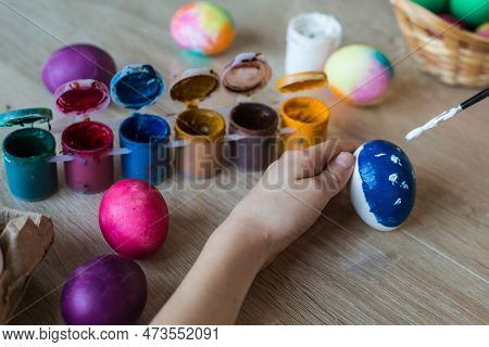 Children's Hands Close-up Paint Eggs With Gouache. A Girl Paints Easter Colored Eggs With Paints And