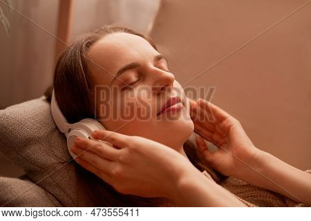Side View Portrait Of Relaxed Young Adult Woman Listening Music While Resting On Couch At Home, Keep