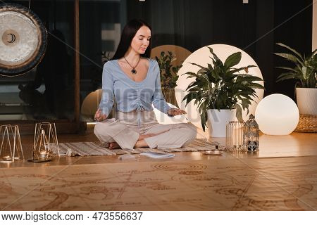 A Young Woman Sitting In The Lotus Position Before The Game Was Playing And Holding Game Cubes In He