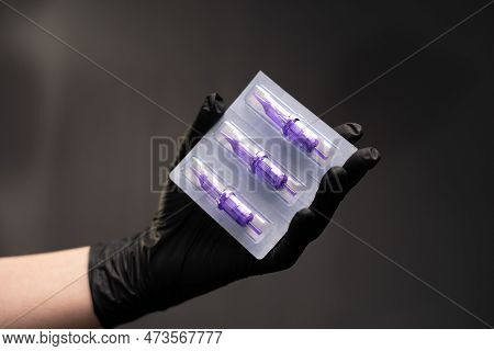 Master Of Permanent Makeup Holds Disposable Needles In Her Hand Over A Black Background. Disposable 