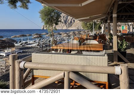 Kamari, Santorini, Greece - July 3, 2021: Sun Loungers On The Black Volcanic Beach Of Kamari In Sant