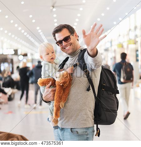 Father Traveling With Child, Holding His Infant Baby Boy At Airport Terminal Waiting To Board A Plan
