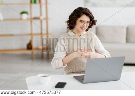 Happy Young Woman In Glasses Teaching Sign Language During Online Lesson Near Devices On Desk.