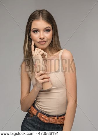 Attractive Girl In Blue Jeans And Long Hair Posing Challenging In Front Of A Background With Wood Ha
