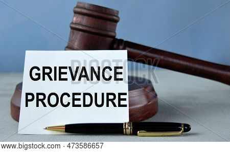 Grievance Procedure - Words On A White Sheet Against The Background Of A Judge's Hammer And A Wooden