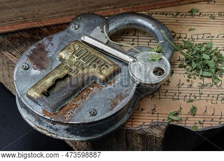 Bangkok,thai - Mar 17, 2023 : The Key And The Vintage Iron Padlock With Chopped Cannabis Leaves On T