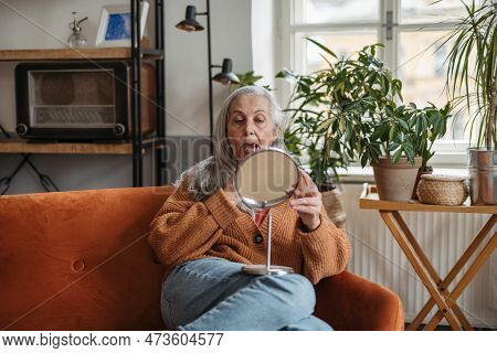 Senior Woman Doing Her Make-up, Sitting In A Living Room.