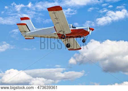 Single Engine Ultralight Plane Flying In The Blue Sky With White Clouds