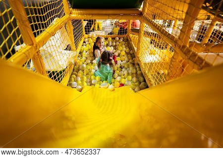 Siblings Play With Colored Balls At Yellow Playground Park. Sisters In Active Entertaiments.