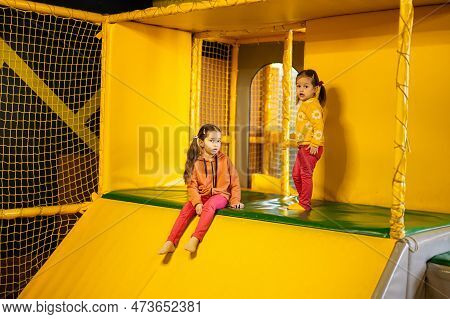 Siblings Sliding At Yellow Playground Park. Sisters In Active Entertaiments.
