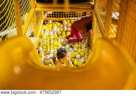 Siblings Play With Colored Balls At Yellow Playground Park. Sisters In Active Entertaiments.