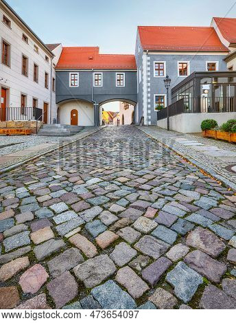 Torgau, Germany. View Of Cobbled Street And Arch In Old Town