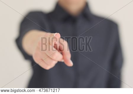 Blurry Woman Points Index Finger To Camera On Beige Background. Female Person Shows Pointing Gesture