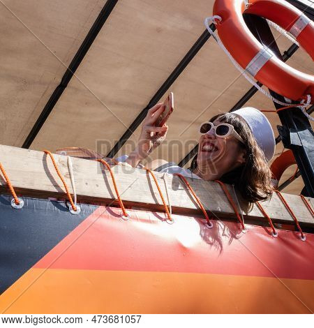 Barcelona, Spain - June 25, 2022: A Mature Woman Takes A Selfie Wearing Sunglasses And A White Hat. 