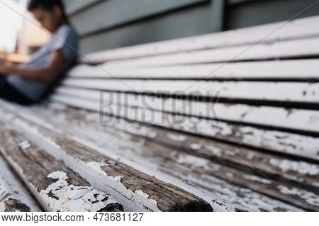 Selective Focus On The Edge Of An Old Abandoned Bench, Details Of Peeling White Paint And Wooden Mat