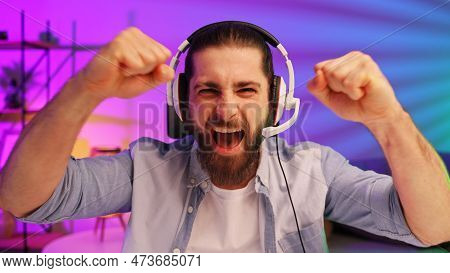 Gamer Bearded Guy, In A Gaming Headset, Wins A Video Game. Cybersportsman In A Neon Room. Lifestyle 