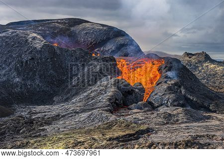 Rising Steam From A Volcano. Lava Flows From A Volcanic Crater. Hot Reddish Liquid Magma Pours Out O