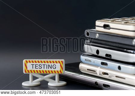 A Lot Of Mobile Phones And Smartphones Next To The Testing Sign. Gadget Testing And Expertise Concep