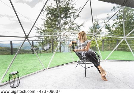 Transparent Bubble Tent At Glamping, Lush Forest Around And Interior. Woman Resting In Glamping