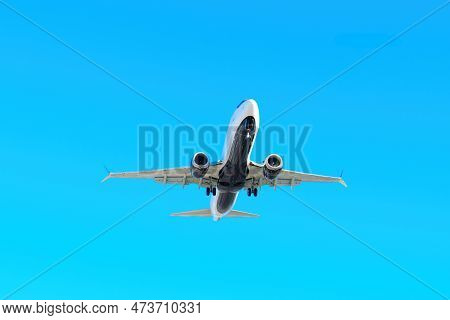 Landing Aircraft's Underbelly In Full View Against A Clear Blue Sky.